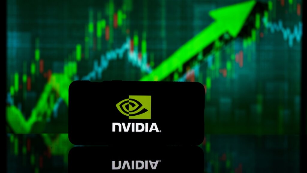 Smartphone mit NVIDIA-Logo auf dem Display vor einem etwas verschwommenen grünen Aktienkurs, der nach oben zeigt.