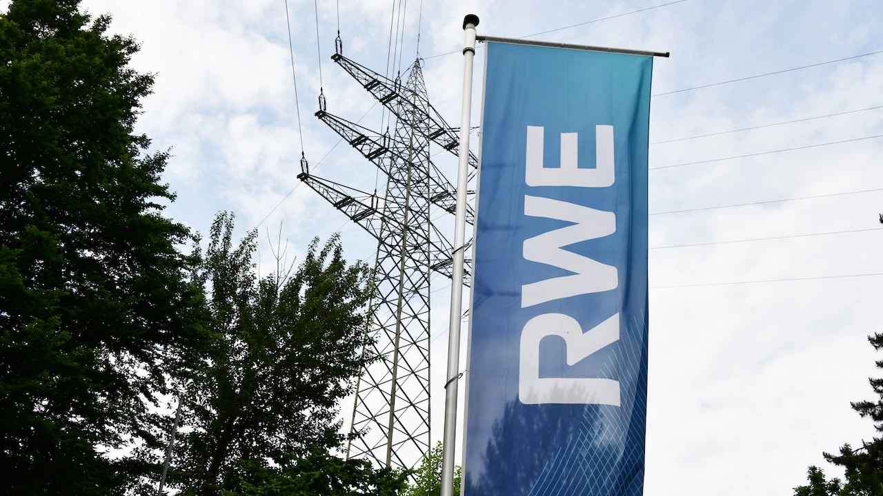 RWE-Fahne vor einem Strommast und Hochspannungsleitungen.