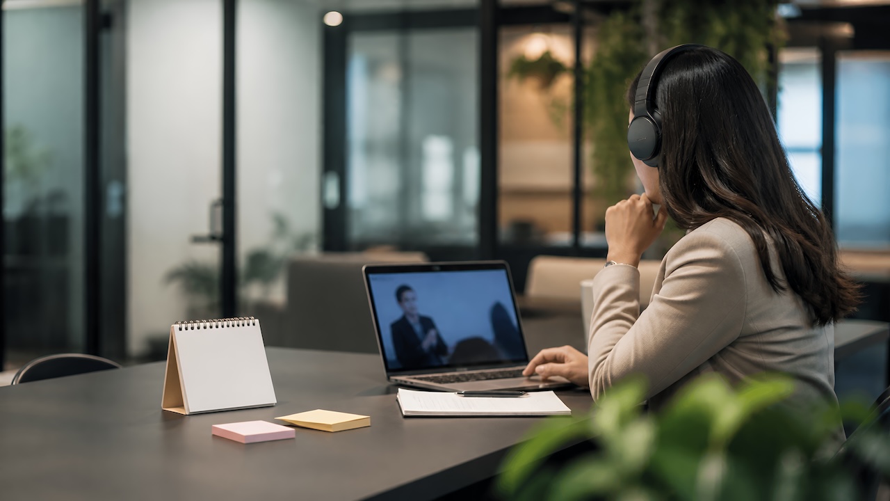 Eine Frau verfolgt im Büro einen Vortrag auf dem Laptop- Bildschirm.