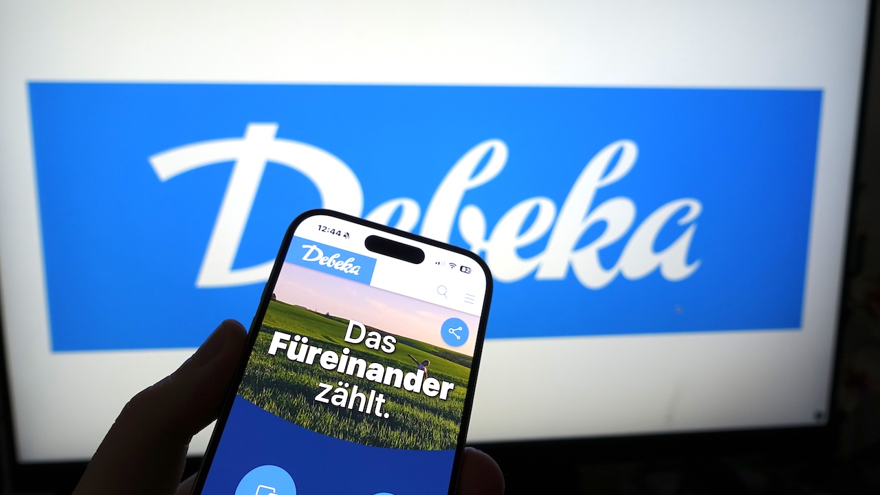 Smartphone, das die Debeka-Website vor einem Firmenlogo auf einem Monitor anzeigt – im Rahmen einer Branding-Präsentation.