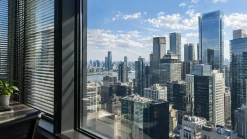 Blick durch ein Bürofenster auf eine Skyline aus modernen Bürohochhäusern bei hellem Tageslicht.